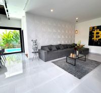 Living room in a villa with a comfortable gray sofa, decorations, and art on the wall.