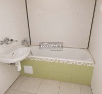A bathroom in a studio apartment with a bathtub and a sink.