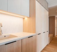 A kitchen in a 3-room apartment with a white countertop and a floor with a wood pattern.