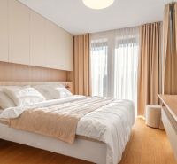 A bedroom with a bed and a wooden decor floor in a 3-room apartment.