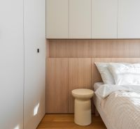 Bedroom with wood-patterned flooring in a 3-room apartment, bed, cabinets, and nightstand.