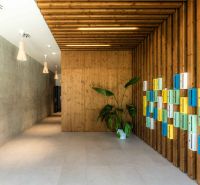 Entrance hall with wooden paneling, colorful mailboxes, and a plant.