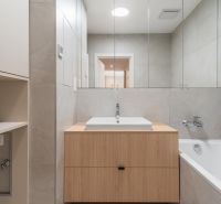 A bathroom with a mirror and a sink on a wooden cabinet in a 3-room apartment.