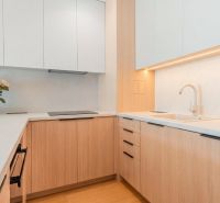 A kitchen in a 3-room apartment with white cabinets and a sink on a floor with a wood decor.