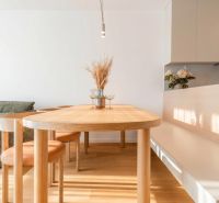 A dining room with a wooden table and chairs in a 3-room apartment, flooring with a wooden decor.