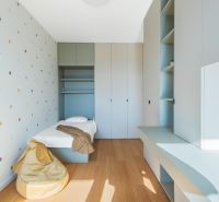 A room in a three-room apartment with a dotted wall, built-in wardrobes, and a floor with a wooden decor.