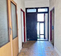 A hallway in a family house with tiles and wooden doors.