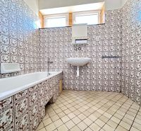 A family house bathroom with retro tiles and a bathtub.