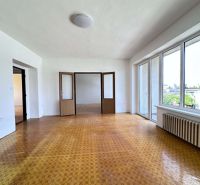 A bright room in a family house with a wood-patterned floor and large windows.