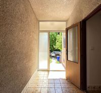 A hallway with decorative tiles leading to illuminated doors in a family house.