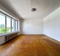 A spacious room with large windows and a wooden decor floor in a family house.