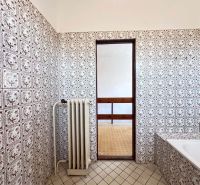 A bathroom in a family house with decorative tiles and a radiator.