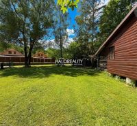 A wooden cottage in Prašice surrounded by a green lawn and trees.