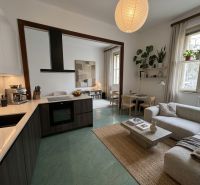 Spacious kitchen and living room in a 3-room apartment with a wooden decor floor.