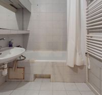 Bathroom in a 3-room apartment with white tiles and a radiator on the wall.