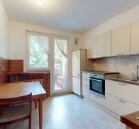 A kitchen in a 3-room apartment with wooden paneling and access to a balcony.