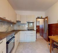 A kitchen in a 3-room apartment with equipment, a floor with a wooden decor, and a dining area.