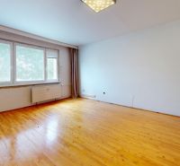 A spacious room with a wooden decor floor and a large window in a 3-room apartment.
