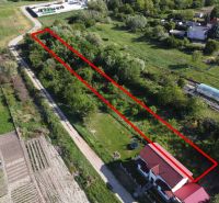A plot of land in the gardens in the village of Branč, bordered by a red line, surrounded by greenery.