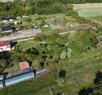 An aerial view of green gardens in Branč with plots and houses.