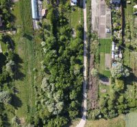 An aerial view of green gardens in Branč, surrounded by trees and fields.