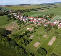 An aerial view of the green gardens in Hruboňovo, surrounded by fields and the village.