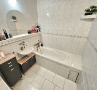 A bathroom in a studio apartment with a bathtub, sink, and storage cabinets.