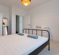 Bedroom in a 2-room apartment with a bed, mirror, and white furniture.