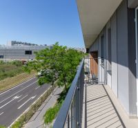 The balcony of the apartment on Zuzany Chalupovej Street in Bratislava, with a view of the road and the building.
