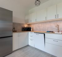 A kitchen in a 2-room apartment with a stainless steel refrigerator and a wooden decor floor.
