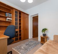 3-room apartment with wooden shelves, a table, and a comfortable armchair.