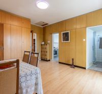 A room with a wooden decor floor, a table, and chairs in a 3-room apartment.
