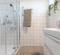 A bathroom in a 3-room apartment with white tiles and a shower corner.