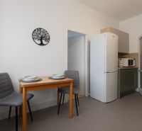 A dining table with two chairs and kitchen appliances in a 3-room apartment.