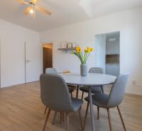 A dining room with a wooden decor floor, a round table, and chairs in a two-room apartment.
