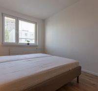 A bedroom with two single beds, a lamp, and a wooden floor in a two-room apartment.