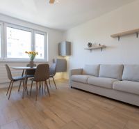 Living room with a dining table, sofa, and wooden decor flooring in a 2-room apartment.
