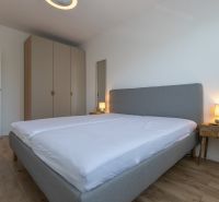 Bedroom with a large bed, wardrobe, and wooden decor flooring in a 2-room apartment.