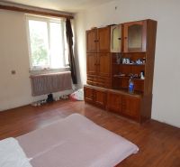 A room in a family house with furniture, a floor with a wooden decor, a window by the radiator.