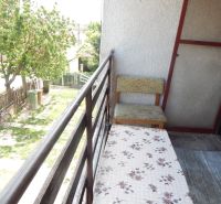 The balcony of a family house in Strekov with seating, a view of the yard, and a tree.