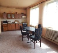 A kitchen in a family house with simple furniture and a radiator under the window.