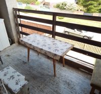A balcony of a family house in Strekov with a simple table and a view of the garden.