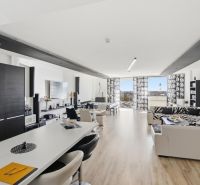 Spacious living area with wood-patterned flooring in a 2-room apartment.