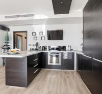 A kitchen in a 2-room apartment with a wood-patterned floor and modern furnishings.