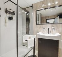 A bathroom in a 2-room apartment with a large mirror and a shower corner.