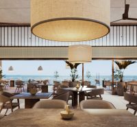 A restaurant with an ocean view, comfortable seating, large hanging lights.