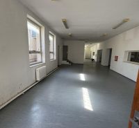 A spacious room with windows and a gray floor in commercial premises.