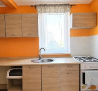 A kitchen in a family house with wooden decor, orange walls, a combination of cabinets and a stove.