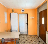 Interior of a family house with orange walls, a table, and decorative paintings.