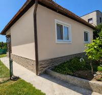 A family house in Demandice with a garden, walkway, and fencing, surrounded by greenery and lawn.